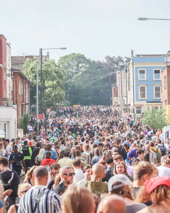 A packed city street event, with the crowd filling the road between terraced houses.